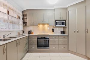 a kitchen with white cabinets and a sink and a microwave at Winnies on Sunpatch in Tomakin