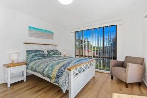 a bedroom with a bed and a chair and a window at Winnies on Sunpatch in Tomakin