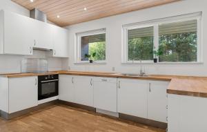 a kitchen with white cabinets and a wooden ceiling at Awesome Home In Bording With Sauna in Korning