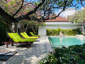a pool with green lounge chairs next to a house at Meditasi Bungalows & Villas in Amed