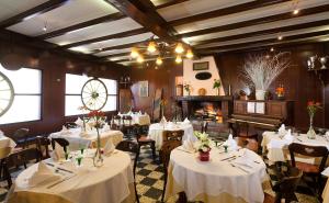uma sala de jantar com mesas e cadeiras brancas e uma lareira em Hotel Restaurant Le Pavillon Carina em Gap