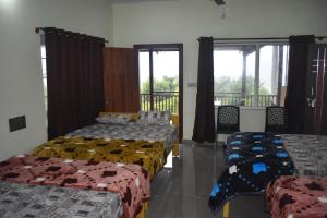 three beds in a room with windows at Naisarga hill view homestay in Somvārpet +48 photos