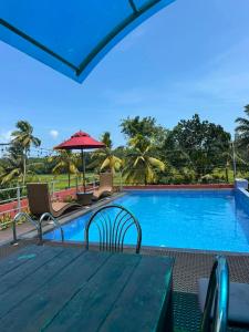 a table with chairs and an umbrella next to a swimming pool at Feather Villa in Talpe