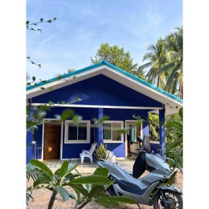 a blue house with a motorcycle parked in front of it at Blue House Klong Hin in Ko Kood