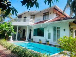a villa with a swimming pool in front of a house at The Negombo Manor Villa in Negombo