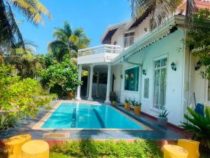 a villa with a swimming pool in front of a house at The Negombo Manor Villa in Negombo