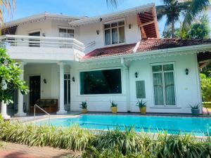 a house with a swimming pool in front of it at The Negombo Manor Villa in Negombo +2 photos