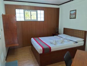 a bedroom with a bed and a table and a window at The Verandah Lodge Bed and breakfast in Banaue