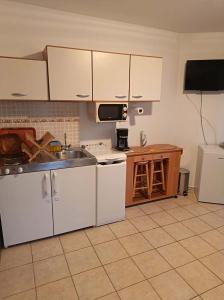 a kitchen with white cabinets and a sink at Elo Apartman in Csokonyavisonta