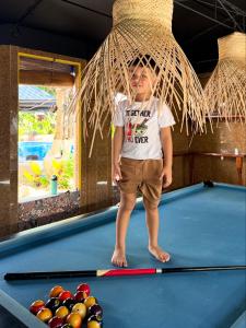 a young boy standing on a pool table at Deep Forest Garden Hotel in Puerto Princesa City