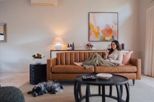 a woman sitting on a couch talking on a cell phone at Clayfields Hunter Valley in Pokolbin