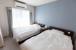 a bedroom with two beds next to a window at 星空テラスと海一望 静寂に包まれる屋上BBQ Resort Villa ManMaka in Miyakojima