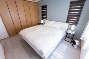 a bedroom with a white bed and a window at 星空テラスと海一望 静寂に包まれる屋上BBQ Resort Villa ManMaka in Miyakojima