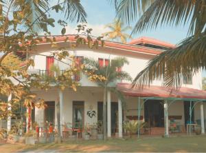 a white house with palm trees in front of it at Suzukis lagoon front in Katunayaka