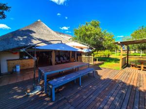 a deck with benches and a thatch roof at Roaring Sky Base Camp in Cullinan