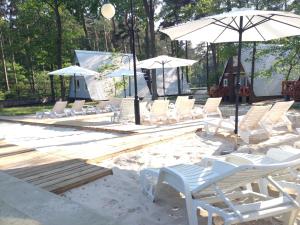 a group of chairs and umbrellas in the sand at Gryf Domki Pobierowo in Pobierowo