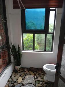 a bathroom with a window and a toilet and rocks at Homestay Hoàng Vũ in Ha Giang