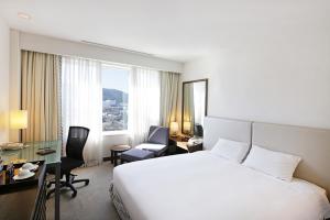 a hotel room with a large white bed and a desk and chair at Geoje Samsung Hotel in Geoje