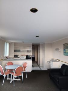 a living room with a table and chairs and a kitchen at Parklane Motel in Launceston