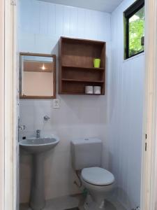 a white bathroom with a toilet and a sink at Hotel Restaurant Paraiso TINY in Villarrica