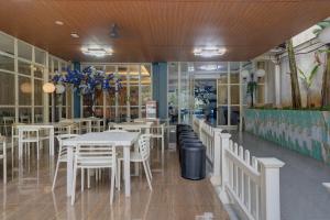 a restaurant with white tables and white chairs at Hotel Bunga-Bunga By ARBA in Jakarta