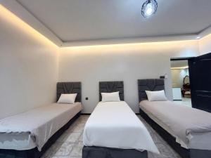 two beds in a room with white walls at Villa TAHA piscine jacuzzi clim in Martil