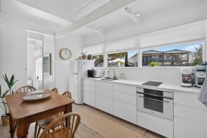 a kitchen with white cabinets and a wooden table at River & Tide escape - On Galpin in Goolwa South