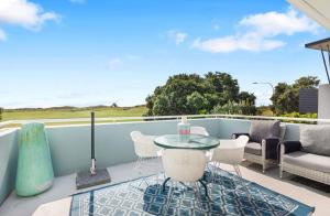 a patio with a glass table and chairs on a balcony at Beach Apartment in Papamoa