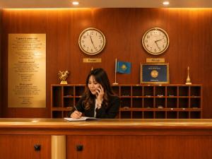 a woman talking on a cell phone at a courtroom with clocks at Marko Polo Hotel in Aksay