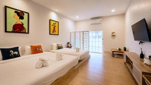 a bedroom with two beds and a flat screen tv at พัทลุงเมริเดียนโฮเทล in Phatthalung