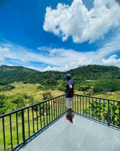 a man standing on the edge of a balcony overlooking a valley at Clay house in Kurukohogama