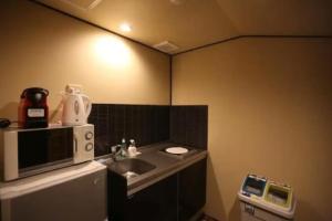 a small kitchen with a sink and a microwave at Machiya Minami Omiya in Kyoto +17 photos