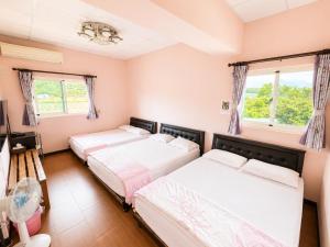 two beds in a room with two windows at Du Du Hao B&B in Yung-an-ts'un
