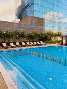 a large swimming pool with chairs and a building at The Signature Suites at Cinnamon life Apartment in Colombo