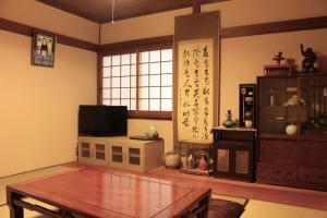a living room with a table and a tv at Jizo House in Kyoto