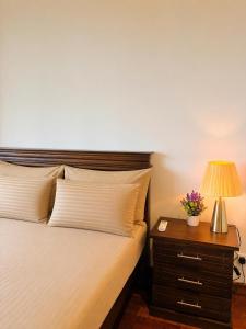 a bedroom with a bed and a nightstand with a lamp at The Signature Suites at Cinnamon life Apartment in Colombo +34 photos