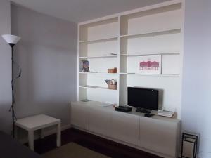 un soggiorno con TV su una parete bianca di Apartamento Fonte Luz II a Matosinhos