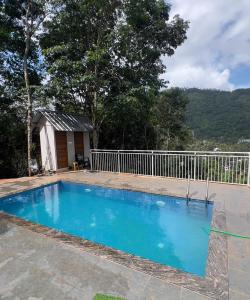 a blue swimming pool in front of a fence at Tribez Valley Resort in Anaviratty