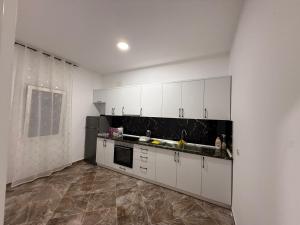 a kitchen with white cabinets and a tile floor at Vila Muhadri in Kamëz