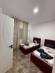 a bedroom with two beds and a door to a room at Vila Muhadri in Kamëz