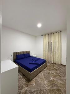 a bedroom with a bed with a blue blanket on it at Vila Muhadri in Kamëz
