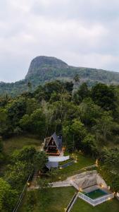 a house in the middle of a field with a mountain at Tribez Valley Resort in Anaviratty +11 photos