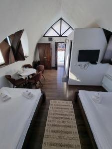 a room with two beds and a flat screen tv at Hunnia - Huntanya in Vlăhiţa