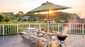 a picnic table with an umbrella on a deck at Ganghwa imspa Pension in Incheon