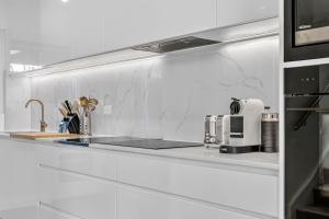 a white kitchen with a sink and a counter top at Sunset Sands on Esplanade By Host Solutions in West Beach