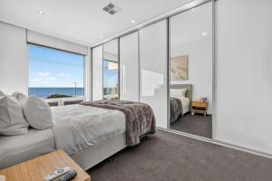a bedroom with a bed and a view of the ocean at Sunset Sands on Esplanade By Host Solutions in West Beach