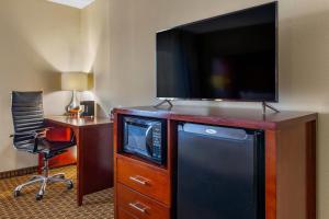 a hotel room with a television on a dresser with a desk at Comfort Inn Fort Mill Amusement Park at Carowinds Blvd in Fort Mill