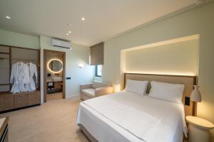 a bedroom with a large white bed and a bathroom at The Palms Kos in Kos