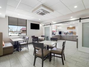 a dining room with tables and chairs and a kitchen at MainStay Suites Chambersburg in Chambersburg