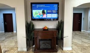 a television on a wall above a fireplace with plants at Quality Inn & Suites McAlester on Hwy 69 in McAlester